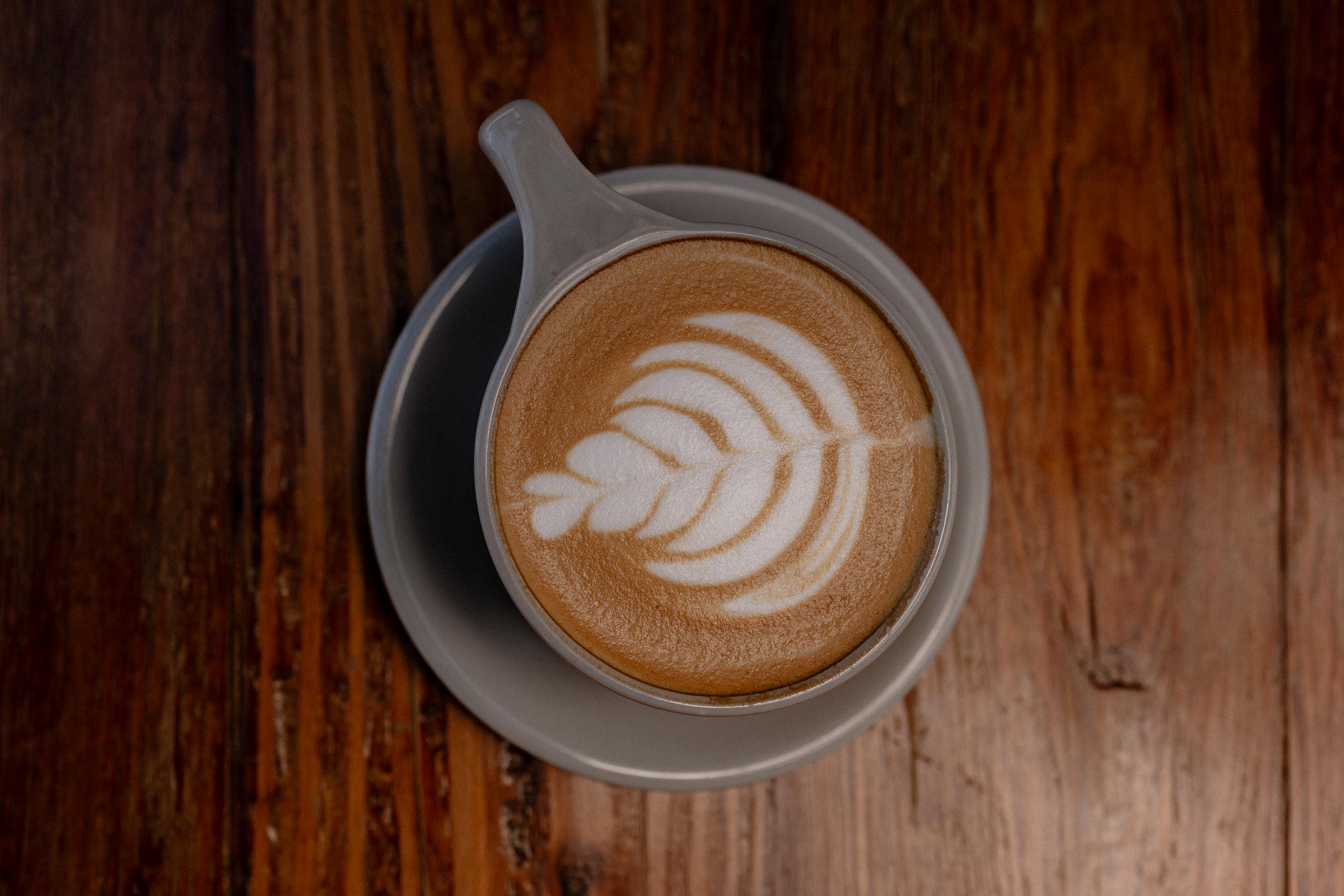 Latte art in a ceramic cup on a wooden table at Kinfolx
